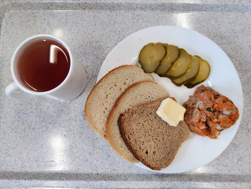 Na zdjęciu znajduje się KOLACJA - DIETA PODSTAWOWA Herbata czarna ekspresowa z cytryną Cateringowa, Chleb mieszany pszenno-żytni, Chleb graham, Masło extra 82%, Pasta z makreli wędzonej z warzywami, Ogórek kiszony